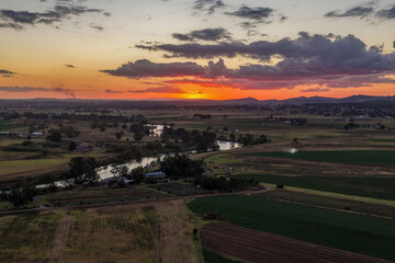 Fototapeta premium Aerial view of colourful sunset over Morpeth River and surrounding farmland in New South Wales, Australia. 