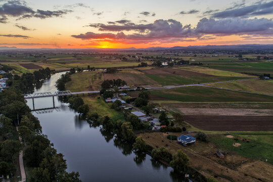 Aerial view of sunset over Morpeth River and bridge in New South Wales, Australia. Scenic landscape showing warm evening light reflecting across water and structure spanning river.
