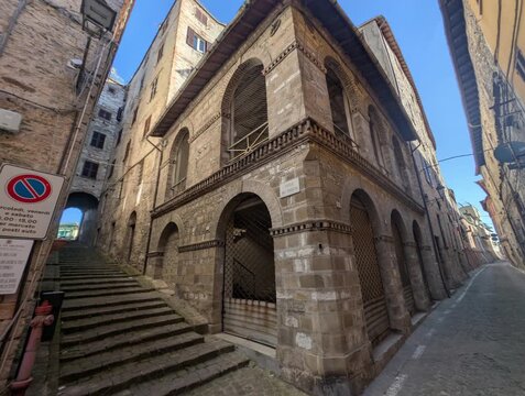 Strada storica in pietra con edificio antico e archi in muratura, situata tra scalinate e vicoli in pendenza. Una scena urbana dal forte carattere medievale