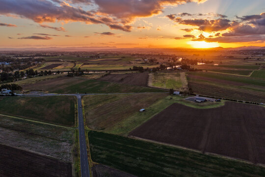 Aerial view of sunset over farmland at Morpeth in New South Wales, Australia. Scenic rural landscape showing warm evening light across agricultural fields and countryside.