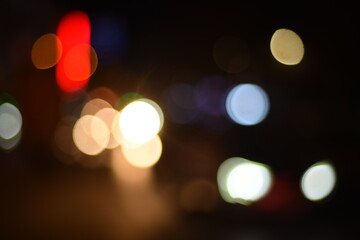 Obraz premium Abstract blurred city lights at night with colorful bokeh effect, featuring warm orange, red, green and yellow glowing circles. Ideal for urban nightlife themes, festive backgrounds, traffic concepts,