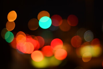 Fototapeta premium Abstract blurred city lights at night with colorful bokeh effect, featuring warm orange, red, green and yellow glowing circles. Ideal for urban nightlife themes, festive backgrounds, traffic concepts,