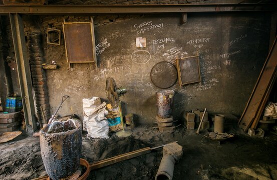 Dhaka, Bangladesh - 20 April 2026: View of a dark, grimy workshop interior, showcasing rough, textured walls with faded writings and industrial tools.