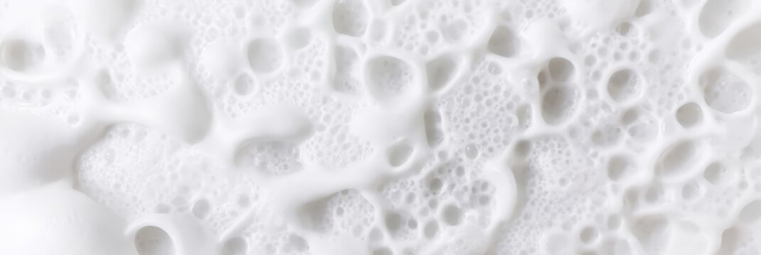 Close-up of white foam bubbles with various sizes and translucent textures, creating a soft, airy pattern that resembles soap suds or frothy liquid.