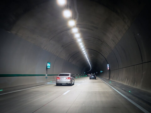 Modern road tunnel interior with cars driving under illuminated ceiling, highlighting fast transit, underground transport, commuting, travel flow and mobility concept.