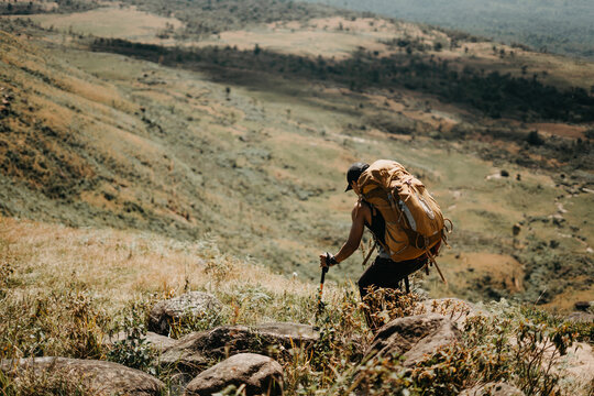 Hiker ascending rocky terrain scenic hilltop landscape outdoor adventure nature exploration dynamic perspective