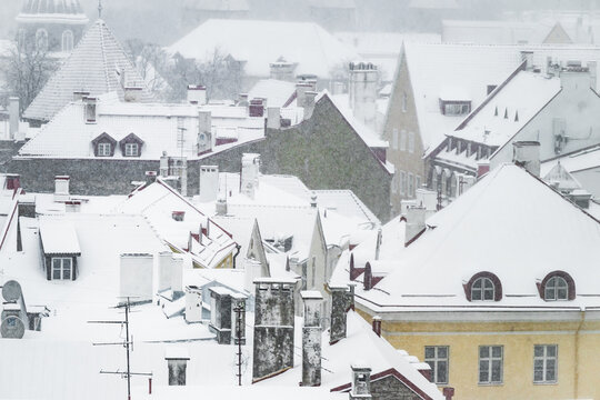 View of a winter scene where rooftops are covered in snow, with various architectural styles and textures creating a monochromatic landscape, Tallinn, Estonia.