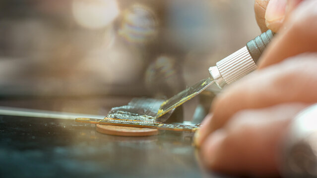 Technician restoring computer connector using special paste in electronics repair workshop