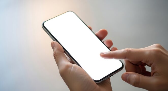 Person's hand holding a modern smartphone with a blank white screen and touching the screen with a finger