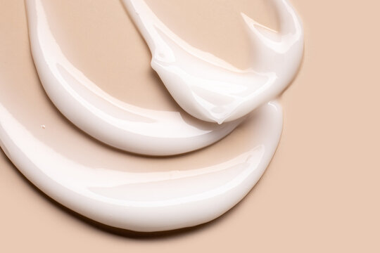 cosmetic smears of creamy texture on a pastel beige background