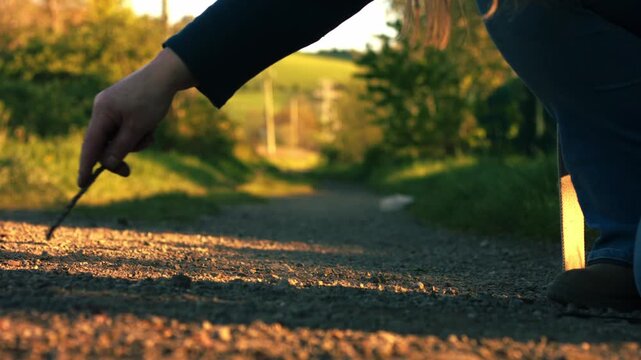 Hand doodling with stick on dusty path