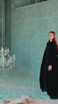 Young beautiful woman in black arab national dress abaya walking barefoot around a large chandelier