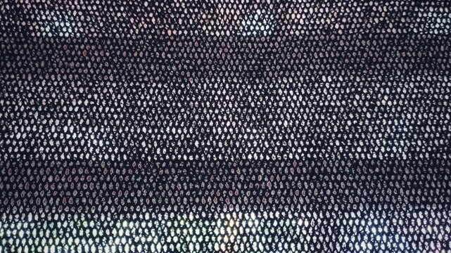 Black perforated mesh texture with light passing through, abstract pattern background, industrial fabric detail, minimal design, high contrast surface, modern backdrop, macro textile structure
