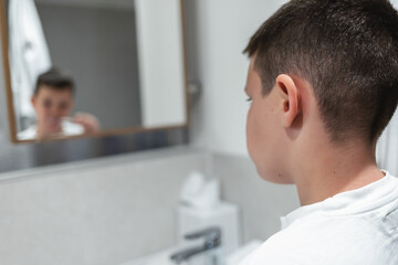 Fototapeta premium Little boy is brushing his teeth at the bathroom sink in the morning.