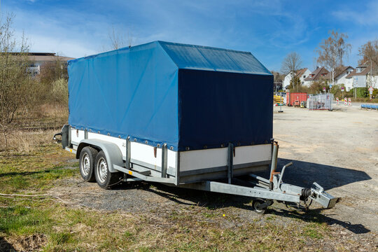 Closed cargo trailer next to site construction site in summer day. Repair works.Vehicle for transporting goods and equipment.
