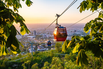 Cable car gondola over Almaty city at colorful sunset with cityscape © Ployker