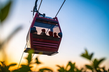 Cable car gondola at golden sunset hour with green foliage foreground © Ployker