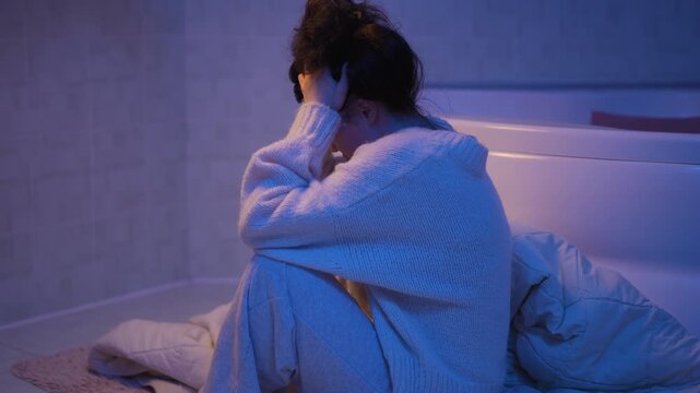 Young desolate woman feeling heartbroken and lonely. Worried and stressed female sitting on the bathroom floor suffers from depression