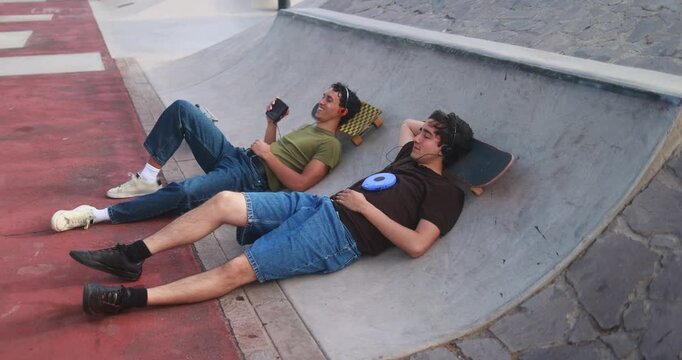 Young friends chilling at skateboard park while listening music with cassette and cd player - New trend, people lifestyle and vintage analog devices