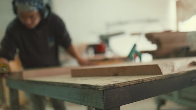 Carpenter measuring wooden plank in workshop