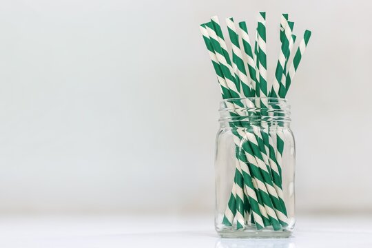 Green and white striped paper straws in a glass mason jar