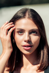 Fototapeta premium Close-up portrait of a young woman with natural makeup and confident expression in daylight