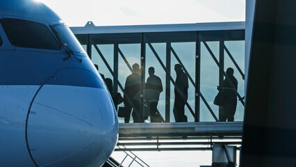 Silhouette of passengers walking through a glass jet bridge to board a large modern airplane at the airport © HABI ANGGARA PUTRA
