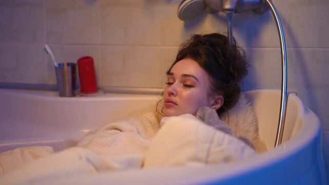 Sad woman with anxiety sleeping in a bathtub with clothes on. Experiencing emotional distress, mental health issues, and loneliness