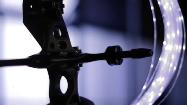 Close up side profile shot of a modern dark composite archery bow mechanism with an arrow cocked in position.