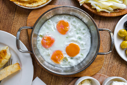 Fresh eggs in a pot served with bread and cheese at a breakfast table in a local eatery in the morning