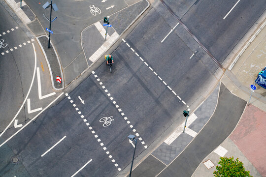 Frankfurt am Main, Germany - 13 April 2017: View of a bustling urban intersection from above, a cyclist navigating stark white road markings on dark asphalt.