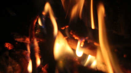 Fototapeta premium Burning log of firewood in fireplace. Close up abstract background Wood fire on black background