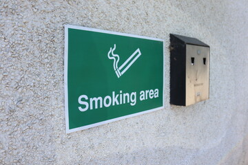 Smoking Area Sign with Wall Mounted Ashtray on Exterior Wall © matthew