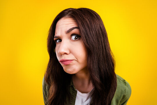 Skeptical young woman making doubtful face in a colorful studio portrait with yellow background