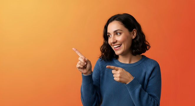 Smiling woman pointing fingers at copy space on orange background, excited female model recommending product, cheerful portrait for advertisement, presenting offer, lifestyle.