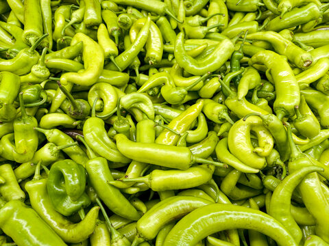 Many green chili peppers arranged together at a market stall in midday
