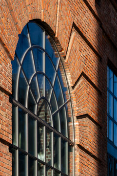 Architecture detail of historic brick facade with arch window where glass reflections and geometry meet for a timeless urban renovation mood