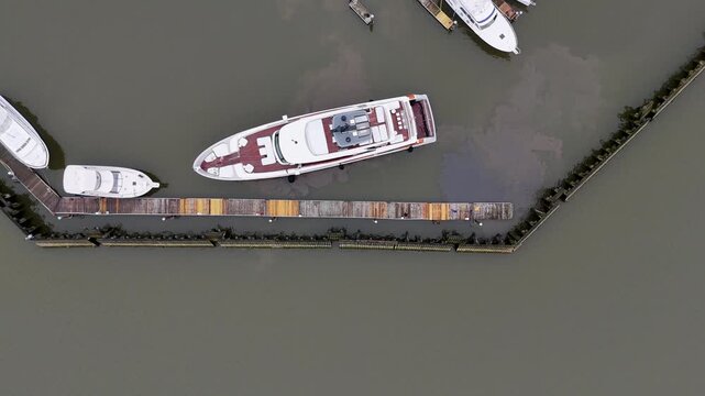 Aerial view of boats at Half Moon Bay Drive marina, with murky brown waters contrasting with the white hulls and weathered wooden docks, Croton-on-Hudson, New York, United States.