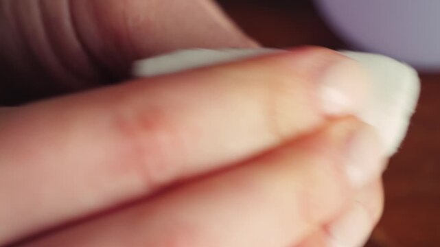 Close-up of hands removing nail polish with a cotton pad and nail polish remover. High quality 4k footage