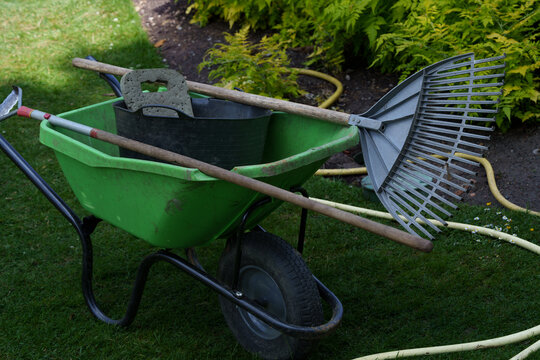 Tools ready early. Garden gear set beforehand. Supplies neatly organized for morning outdoor yard work. Gardening tools and outdoor equipment meticulously laid out on wellkept grass for morning tasks.