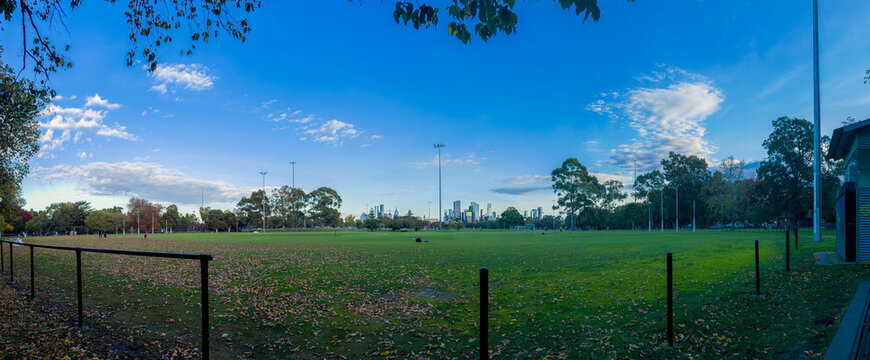 Carlton, Victoria, Australia, April 26th 2026: Panoramics of Melbourne's Princes Park capture a vibrant late afternoon scene, featuring local residents playing sport against a stunning city skyline