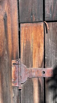 selective focus rusty metal hinge on aged wooden surface close-up