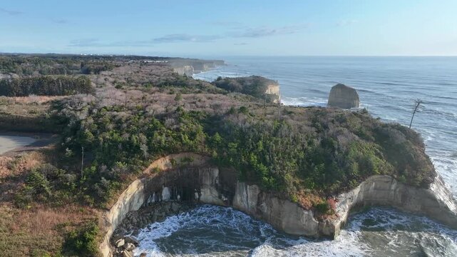 Aerial flyover of rugged cliff coastline with rough waves, Tomioka Fukushima Japan