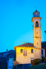 View of the facade and bell tower of Madonna del Sasso Sanctuary, over the western banks of the lake (UNESCO Site), illuminated by artificial lights at the summer dusk. © stefanopez