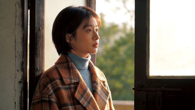 Woman in plaid coat by window