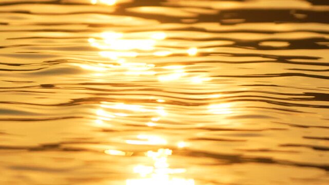 Abstract sea summer ocean sunset nature background. Small waves on golden water surface in motion blur with golden bokeh lights from sun. Holiday, vacation and recreation. Weather and climate change