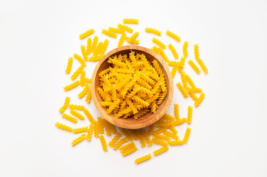 Fusilli, spiral pasta in wooden bowl on white background, top view. Raw, uncooked pasta, food made from wheat flour. Macaroni Mockup. Food background