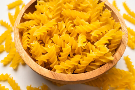 Fusilli, spiral pasta in wooden bowl on white background, top view. Raw, uncooked pasta, food made from wheat flour. Macaroni Mockup. Food background