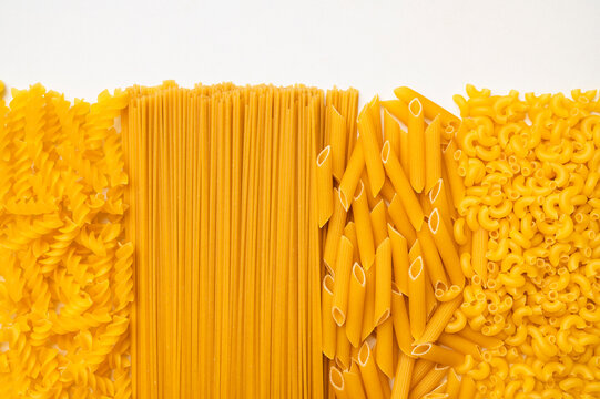 Background of uncooked macaroni of various shapes. Italian pasta close-up. Fusilli, penne pasta, spaghetti. Healthy food made from wheat flour