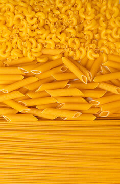 Background of uncooked macaroni of various shapes. Italian pasta close-up. Fusilli, penne pasta, spaghetti. Healthy food made from wheat flour